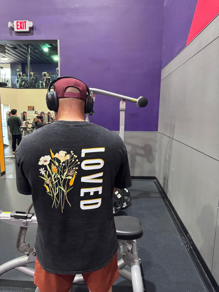 man at gym wearing black shirt with summer flowers and the word LOVED.