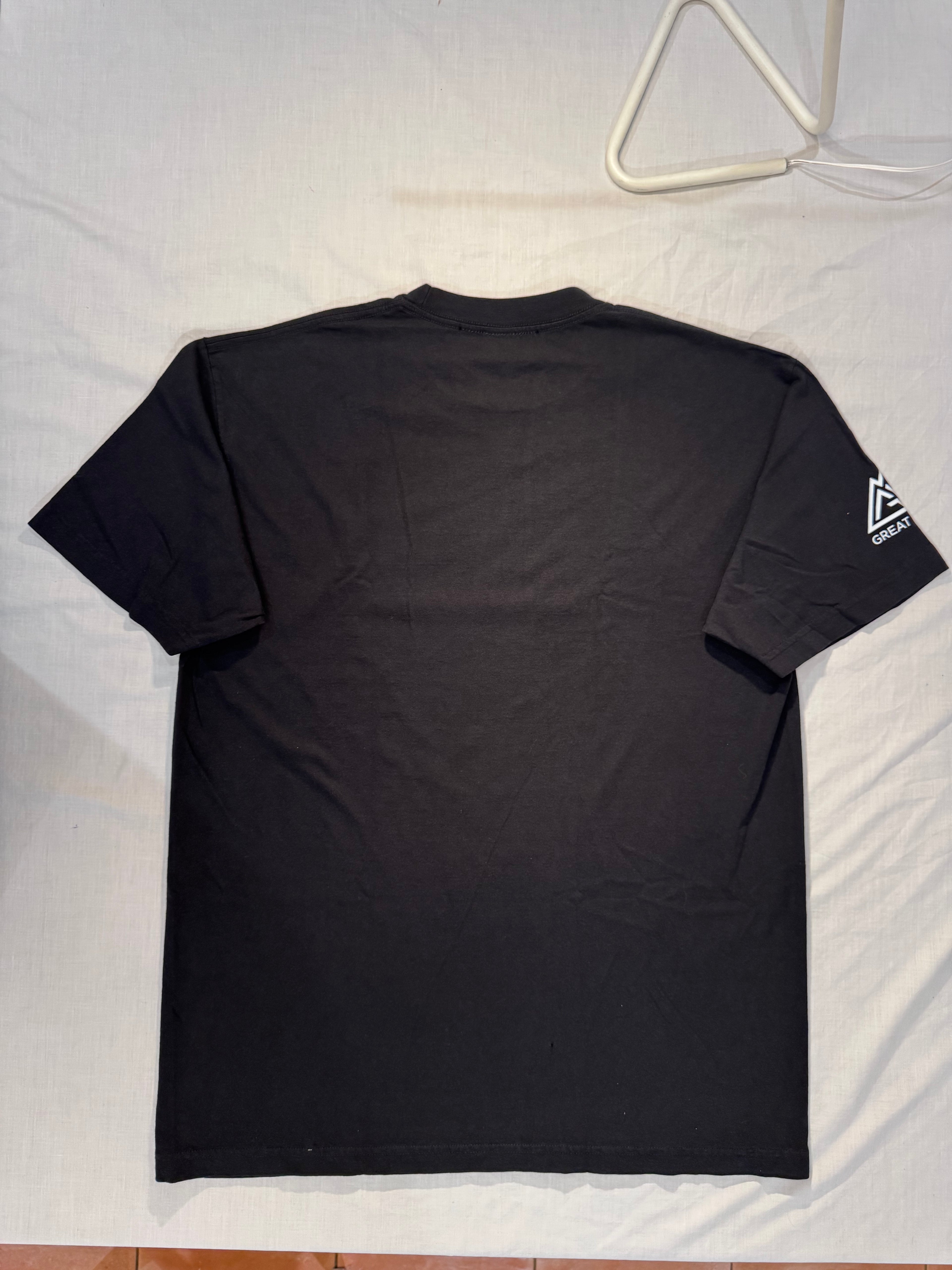Black t-shirt with a logo on the back, hanging on a white hanger against a light background.